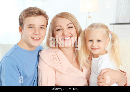 Niedliche Kinder mit Großmutter im Wohnzimmer Stockfoto