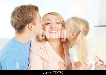 Niedliche Kinder mit Großmutter im Wohnzimmer Stockfoto