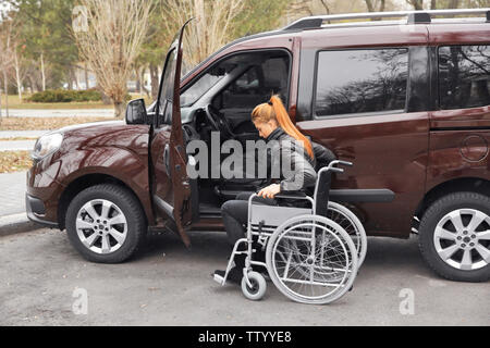 Junge Frau in einem Rollstuhl neben ihrem Auto Stockfoto