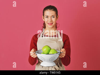 Frau mit Äpfel im Sieb auf farbigen Hintergrund Stockfoto