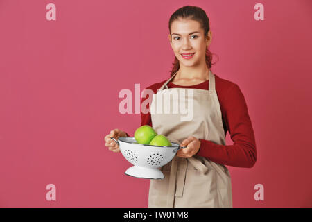 Frau mit Äpfel im Sieb auf farbigen Hintergrund Stockfoto