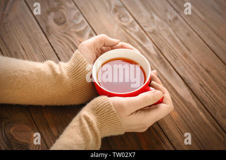 Weibliche Hände halten Tasse aromatischen Kaffee auf hölzernen Hintergrund Stockfoto