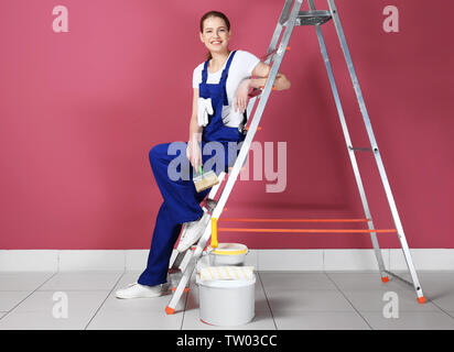 Schöne junge dekorateur sitzen auf Leiter in leere Zimmer Stockfoto