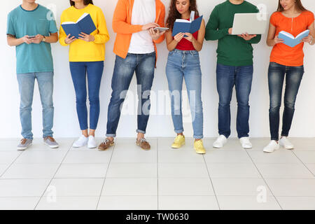 Menschen mit Bücher und Geräte stehen in der Nähe von hellen Wand Stockfoto