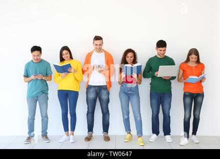 Menschen mit Bücher und Geräte stehen in der Nähe von hellen Wand Stockfoto