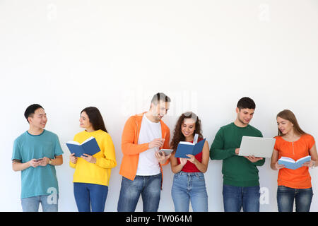 Menschen mit Bücher und Geräte stehen in der Nähe von hellen Wand Stockfoto