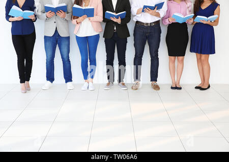 Gruppe von Menschen, die Bücher lesen, während man in der Nähe von hellen Wand Stockfoto