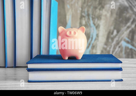 Sparschwein mit Büchern auf hölzernen Tisch Stockfoto