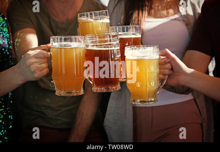 Menschen klirren Becher mit einem Bier in der Kneipe, Nahaufnahme Stockfoto