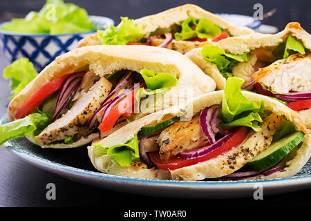 Fladenbrot gefüllt mit Hähnchen, Tomaten und Salat auf Holz- Hintergrund. Nahöstlichen Küche. Stockfoto