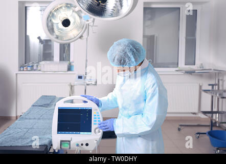Junger Arzt Einstellen der Geräte im Operationssaal der modernen Klinik Stockfoto