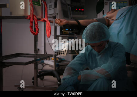 Traurig Arzt sitzen auf dem Boden nach fehlgeschlagenen Operation in der Klinik Stockfoto