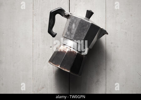 Alten Italienischen moka Topf legen auf grau Holztisch. Es ist eine alte Herd - top Kaffeemaschine, Kaffee brüht, indem Sie kochendes Wasser unter Druck durch Dampf thro Stockfoto
