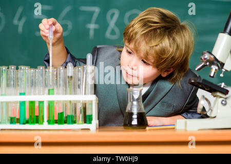 Schule Bildung. Biologische Moleküle erkunden. Kleinkind genius Baby. Junge in der Nähe von Mikroskop und Reagenzgläser in der Schule Klassenzimmer. Technik und Wissenschaft Konzept. Kid studiere Biologie und Chemie in der Schule. Stockfoto