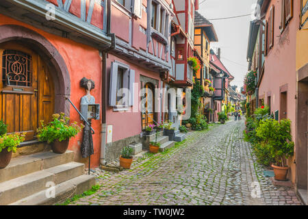 Blühende Gasse im Dorf Eguisheim, Elsass, Frankreich, bunte ursprüngliche Fachwerkhäuser mit Erkern Stockfoto