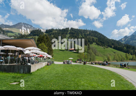 Schwarzsee, FR/Schweiz - vom 1. Juni 2019: Touristen genießen Sie einen Tag und eine Pause im Restaurant am Ufer des Schwarzsee im Kanton Freiburg Stockfoto