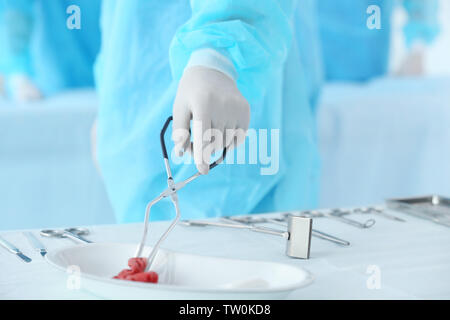 Hand der Arzt die blutigen Gaze in speziellen Becken während des Betriebs in der Klinik Stockfoto