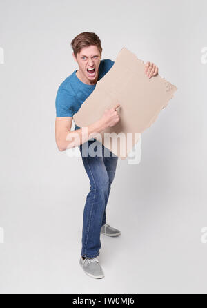 Protestieren junge Mann holding Stück Pappe mit Platz für Text auf hellem Hintergrund Stockfoto