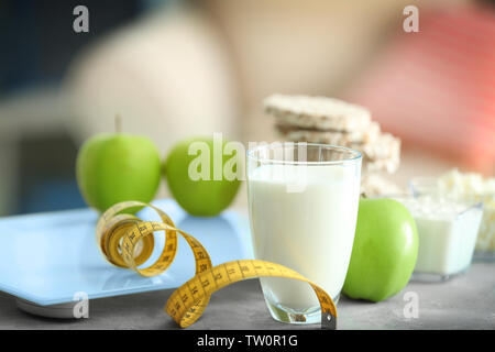 Glas Milch, Apfel, Maßband und Skalen auf Tisch Stockfoto