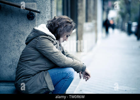 Attraktive Frau, die unter Depressionen leiden Holzeinschlag untröstlich traurig, unglücklich und einsam sitzen in Stadt Urban Street in der psychischen Gesundheit emotionalen Schmerz Abu Stockfoto