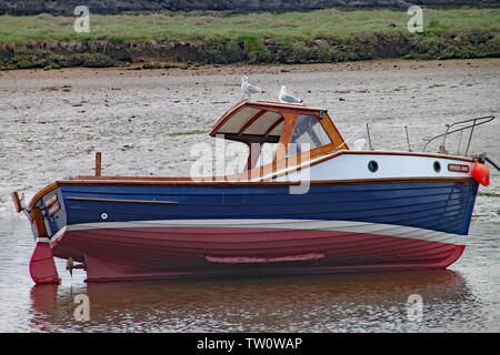 SEATON, Devon, England - 22. MAI 2012: Ein kleines Fischerboot liegt auf seiner Seite bei Ebbe auf dem Fluss Ax Mündung. Zwei Möwen sind auf der thront Ca Stockfoto