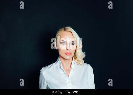 Studio Portrait einer attraktiven Blondine business Frau in einem weißen Hemd und schwarzen Hosen gegen einfachen Hintergrund Stockfoto