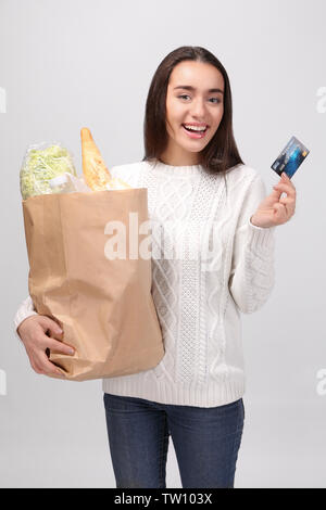 Junge Frau mit papiertüte auf hellen Hintergrund Stockfoto