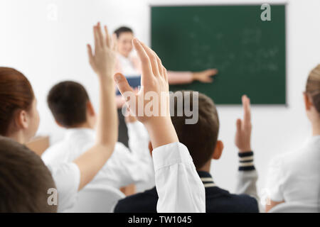 Schüler heben die Hände für die Antwort während der Lektion Stockfoto