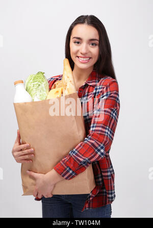 Junge Frau mit papiertüte auf hellen Hintergrund Stockfoto