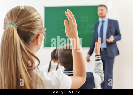 Schulmädchen anheben Hand für Antwort während der Lektion Stockfoto