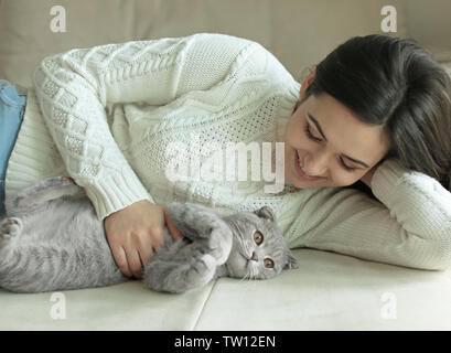 Schöne junge Frau mit niedlichen Katze zu Hause ausruhen Stockfoto