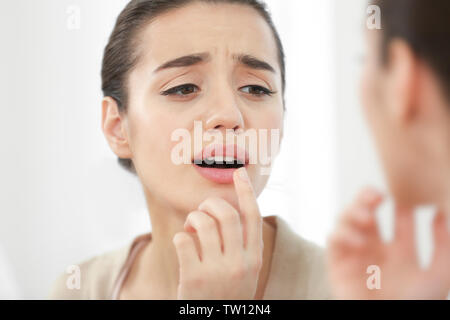 Schöne Frau Anwendung Creme auf die Lippen in der Nähe von Spiegel Stockfoto