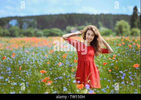 Reizende junge romantische Frau im Stroh Hut auf poppy flower Feld auf Hintergrund Sommer posieren. Tragen Strohhut Stockfoto
