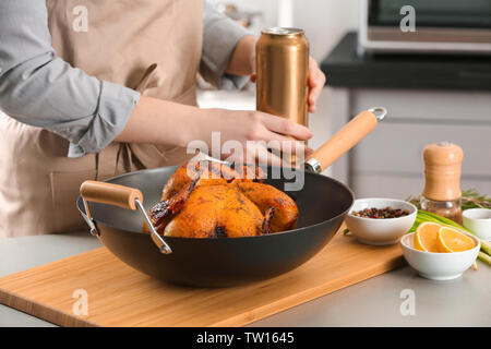 Frau mit gegrillten Bier kann Huhn im Topf auf Schneidebrett Stockfoto