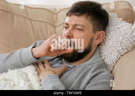 Junge kranke Mann auf dem Sofa zu Hause liegen Stockfoto
