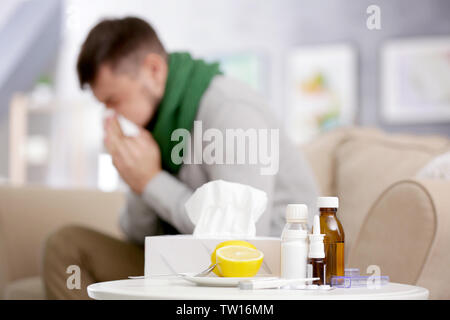 Satz von Medikamente, elektronische Thermometer und Zitronen mit unscharfen kranker Mann im Hintergrund Stockfoto