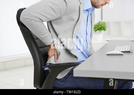 Menschen mit Rückenschmerzen in einem Sessel im Büro, Nahaufnahme Stockfoto