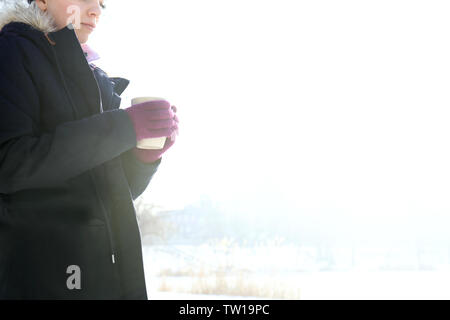Weibliche Hände in niedlichen rosa Handschuhe holding Schale auf Winter Hintergrund Stockfoto