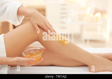 Junge Frau depilating Beine mit flüssigem Zucker in Spa Stockfoto