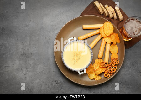 Fach mit Bier Käse dip und Snacks auf Tisch Stockfoto
