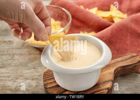 Weibliche Hand tauchen Nacho in Schüssel mit Bier Käse dip, Nahaufnahme Stockfoto