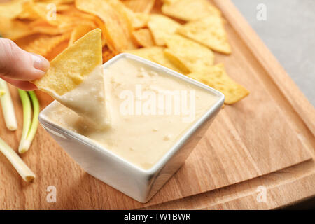 Weibliche Hand tauchen Nacho in Schüssel mit Bier Käse dip, Nahaufnahme Stockfoto