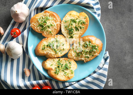 Leckere Brotscheiben mit geriebenem Käse, Knoblauch und Kräutern auf Platte Stockfoto