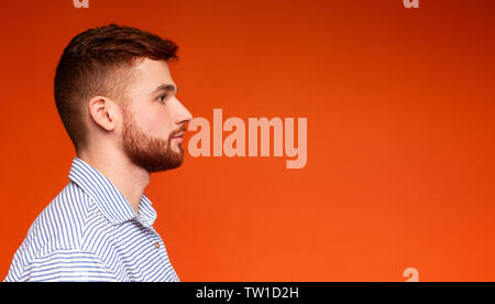 Seitenansicht Portrait von konzentrierten jungen Mann weg bei copy Space auf orangem Hintergrund, Panorama, freier Speicherplatz Stockfoto