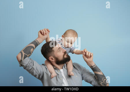 Stattliche tätowierten jungen Mann mit niedlichen kleinen Baby auf hellen Hintergrund Stockfoto