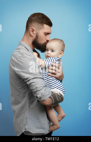 Stattliche tätowierten jungen Mann mit niedlichen kleinen Baby auf hellen Hintergrund Stockfoto