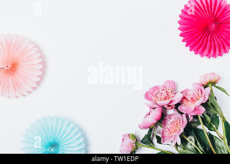 Festliche flach Hintergrund von Urlaub Seidenpapier Dekorationen und Strauß mit frischen Blumen auf weiße Pfingstrose Tabelle, Ansicht von oben. Stockfoto