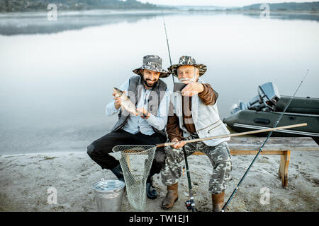 Großvater mit Sohn Spaß, wodurch selfie Foto zusammen mit fangfrischem Fisch auf dem See in den frühen Morgenstunden Stockfoto