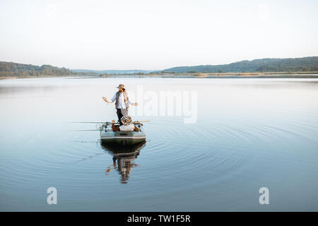 Glückliche Menschen, die frisch gefangenen Fische beim Stehen auf dem Boot mit Großvater auf den See in den frühen Morgenstunden Stockfoto