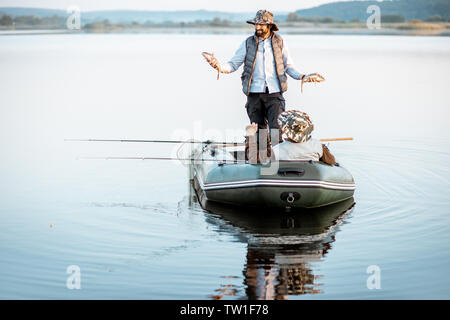 Glückliche Menschen, die frisch gefangenen Fische beim Stehen auf dem Boot mit Großvater auf den See in den frühen Morgenstunden Stockfoto